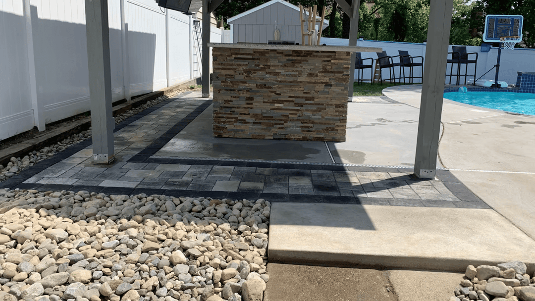 Outdoor patio with stone bar, poolside seating, and landscaped gravel area. Perfect for entertaining.
