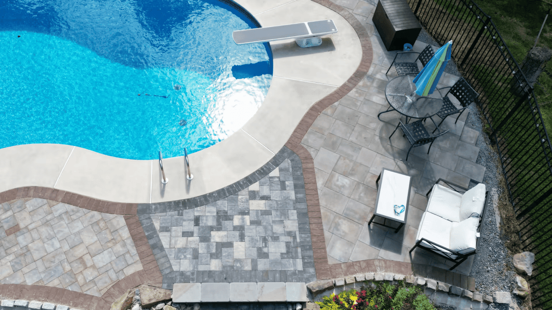 Aerial view of a backyard pool with surrounding patio, lounge chairs, and table.