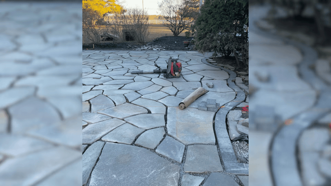 Paved stone patio under construction with equipment and rolled materials.