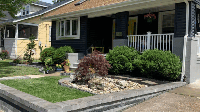 Charming suburban home with landscaped garden, stone pathway, and decorative shrubs.