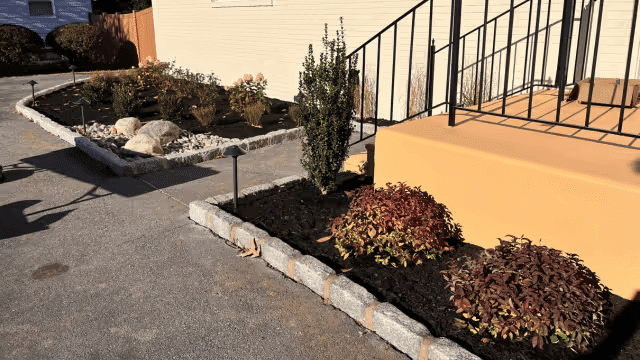Well-maintained landscape with shrubs, rocks, and a stone pathway leading to stairs.