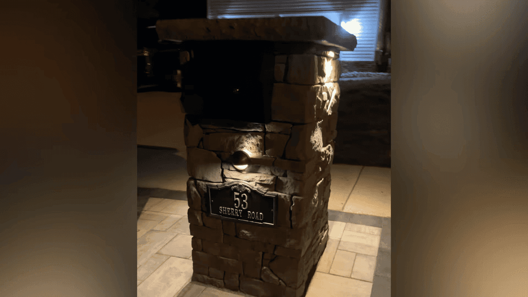 Decorative stone mailbox post with illuminated address sign for 53 Serenity Road.