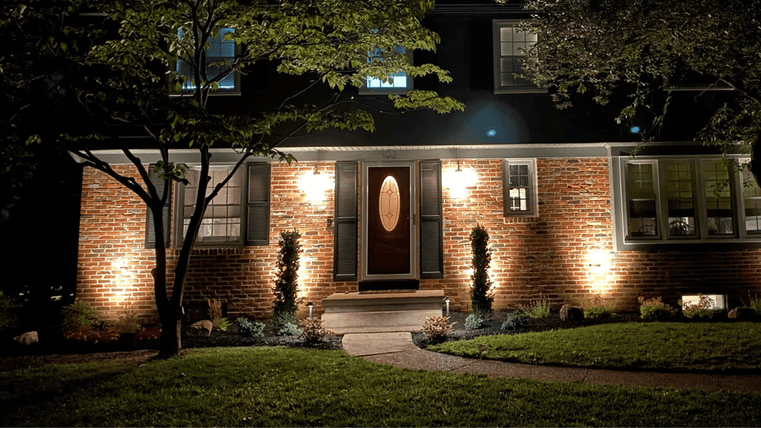 Beautifully lit brick house at night with landscaped garden and pathway.