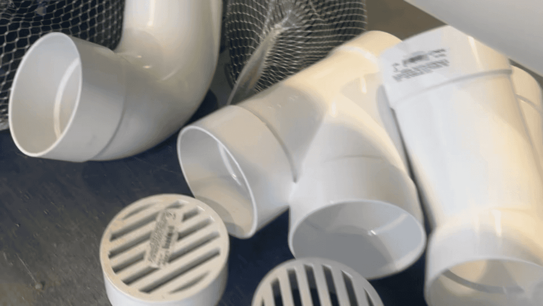 Assorted white PVC pipes and fittings scattered on a workbench.