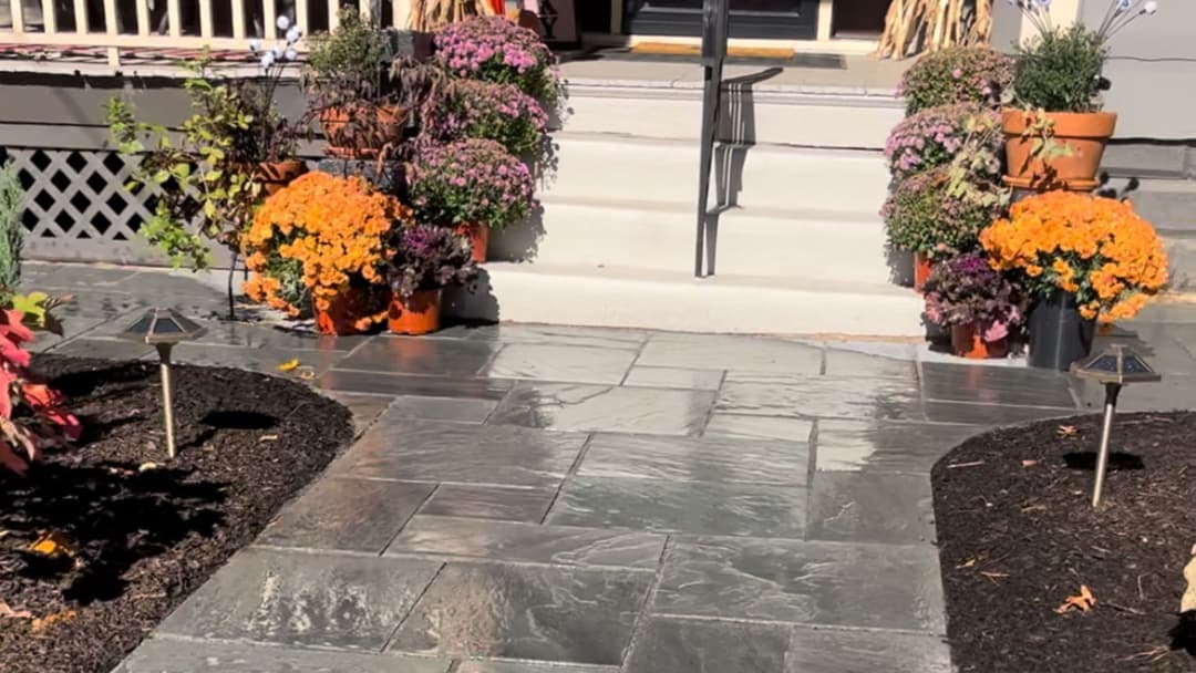 Welcoming front entrance with slate pathway, vibrant flower pots, and seasonal decorations.