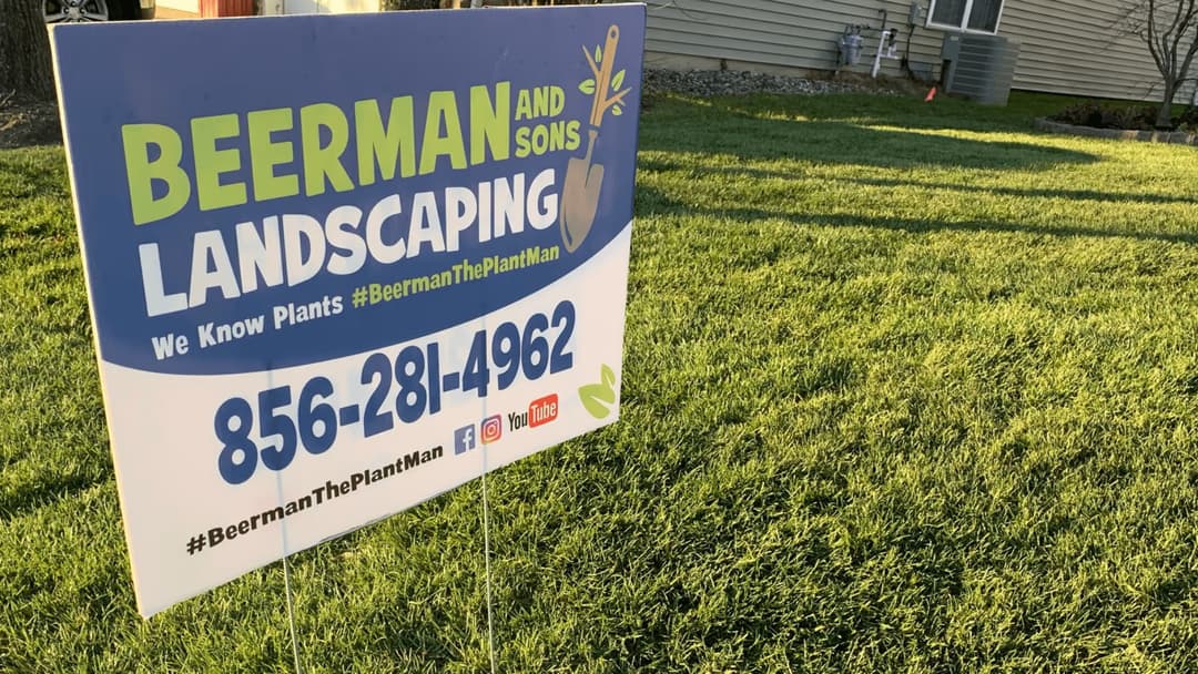 Beerman and Sons Landscaping sign with contact info and social media details on green lawn.