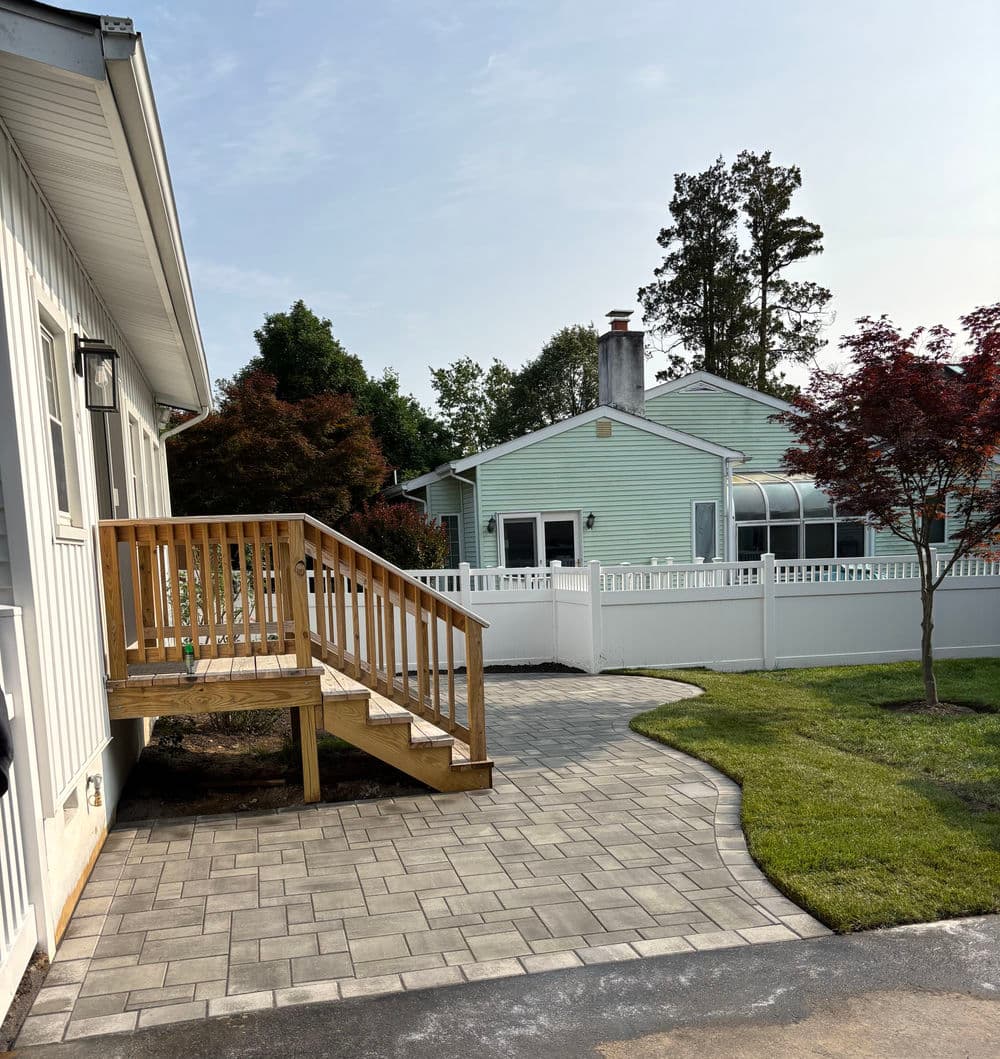 Wooden ramp leading to a house, with paver pathway and green yard in a residential neighborhood.