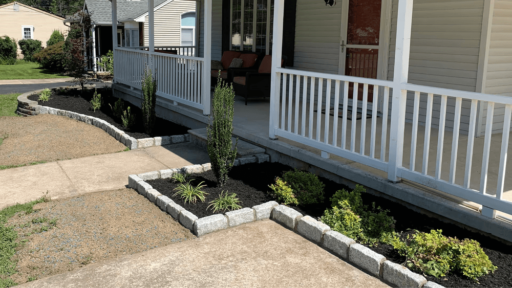 Lush landscaped garden with stone borders and a welcoming front porch.